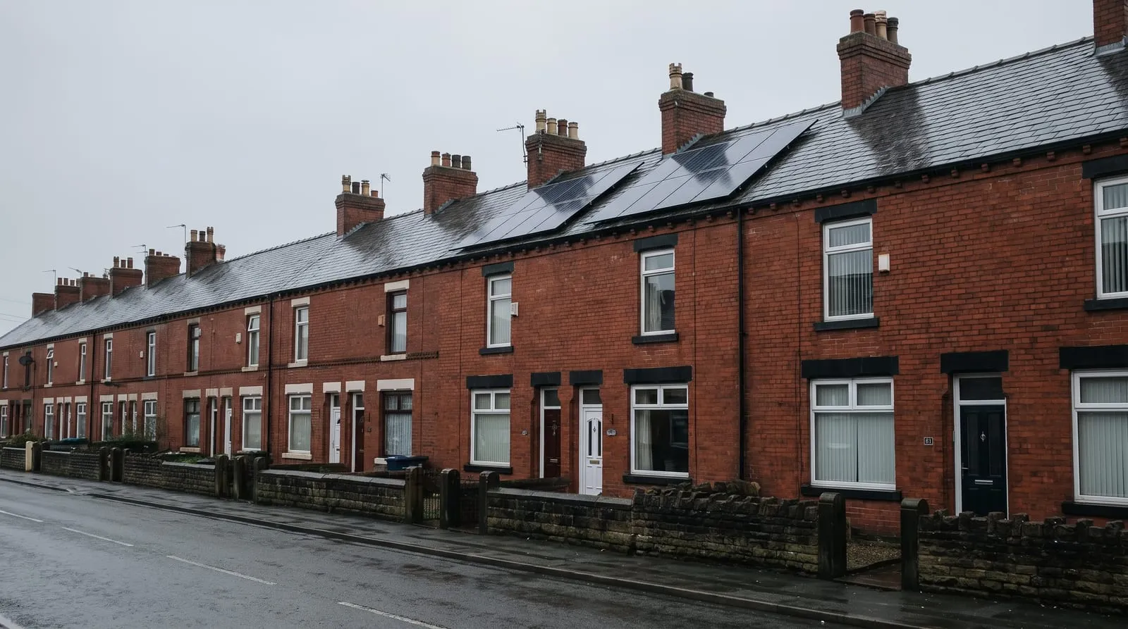 A row of red brick Victorian terraced houses with solar panels on the slate roofs