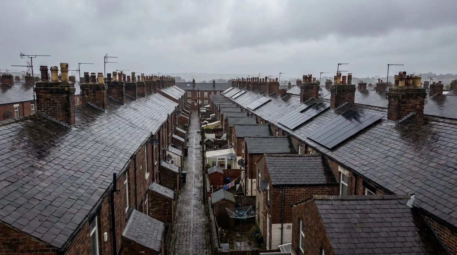 Rows of terraced rooftops seen from above, some with solar panels
