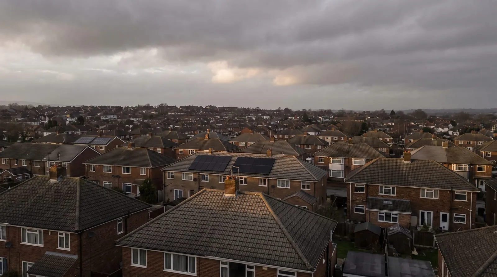 Rooftops across a suburban estate, some carrying solar panels